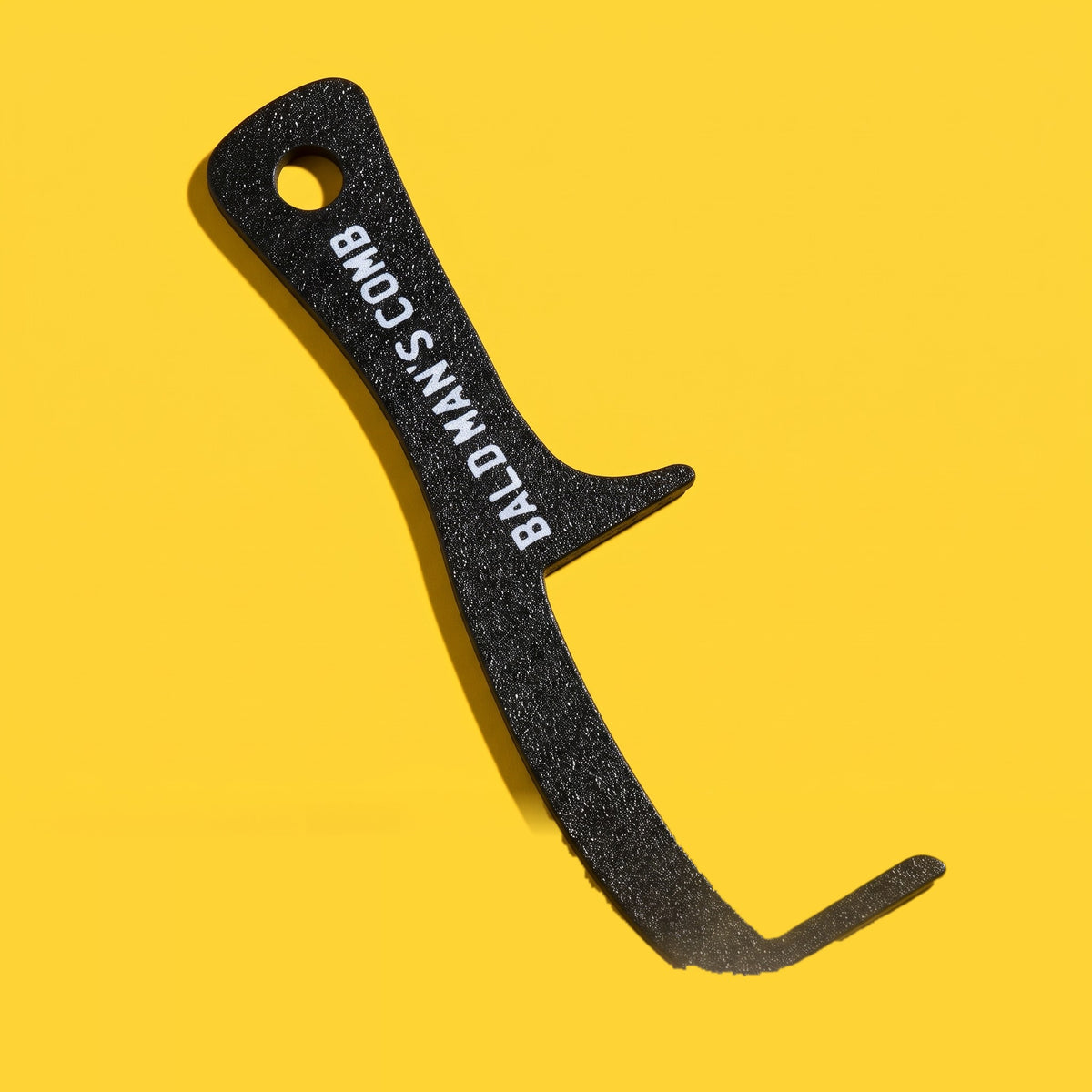 Peine de broma sin púas para calvos, negro con la inscripción BALD MAN'S COMB, sobre fondo amarillo